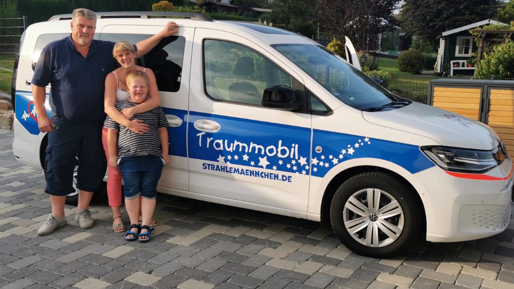 Familie steht gemeinsam vor dem Fahrzeug