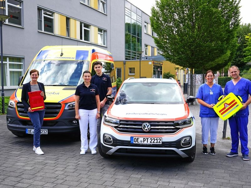 Mitarbeitende von Strahlemaennchen und einem Kinderpalliativteam vor zwei Einsatzfahrzeugen