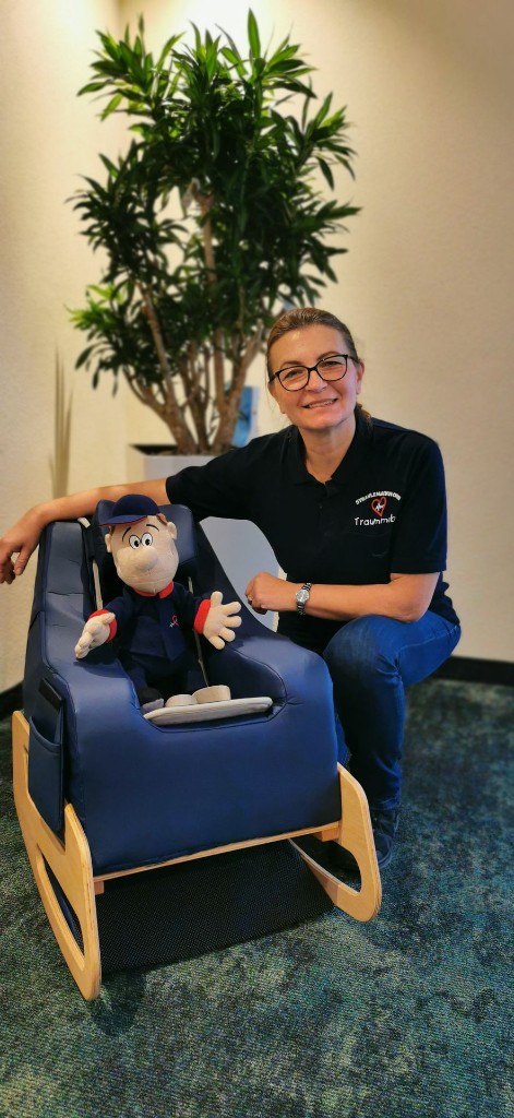 Joanna Junge, Gründerin und Geschäftsführerin, mit einem Strahlemaennchen-Maskottchen in einem Therapiesitz